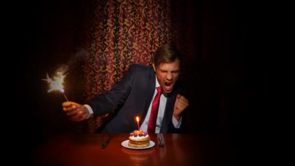 un hombre solitario celebra una fiesta, se sienta solo en una mesa con un pastel y una vela. 4k, cámara lenta
 - Metraje, vídeo