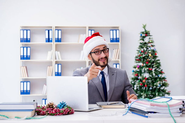 Молодой бизнесмен празднует Рождество в офисе - Фото, изображение