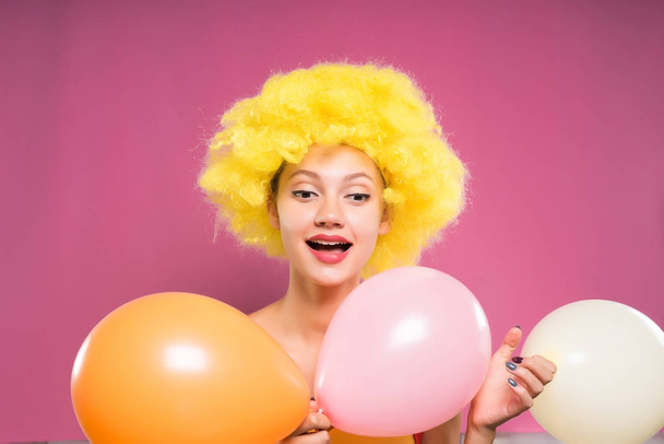 cheerful smiling girl in a bright yellow wig holding three balls in hands - Foto, Imagen