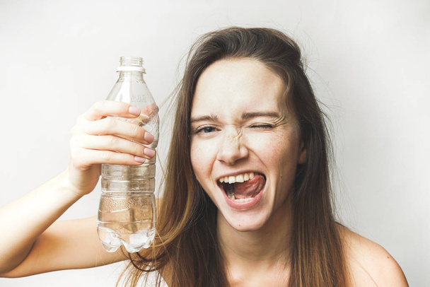 Flirting female with bottle of water, healthy white teeth - Photo, image
