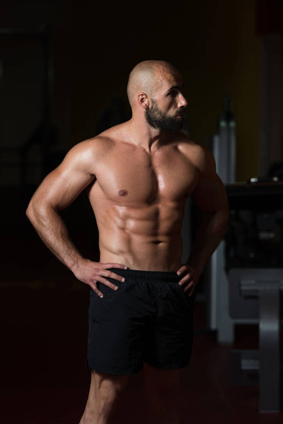 Muscular Man Flexing Muscles In Gym - Foto, immagini