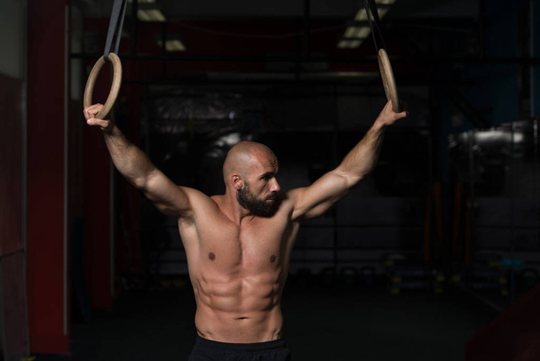 Muscular Athlete Hanging On Gymnastic Rings - Foto, Imagen