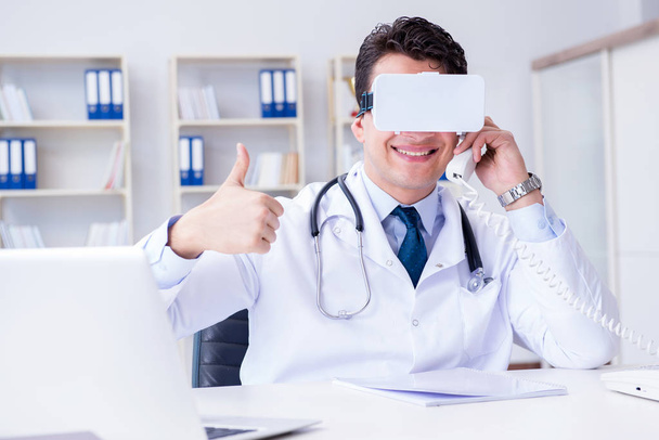 Молодой врач с гарнитурой виртуальной реальности работает в оффи - Фото, изображение