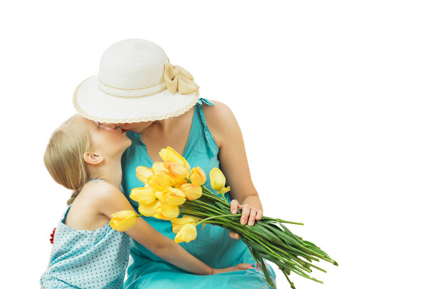 Moeder met haar dochter in blauwe jurken met een boeket van tulpen geïsoleerd op witte achtergrond. - Foto, afbeelding