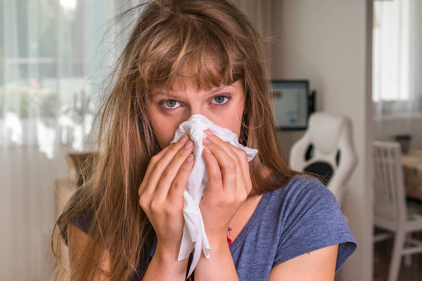 Больной женщиной с гриппом или холодным чиханием в носовой платок
 - Фото, изображение