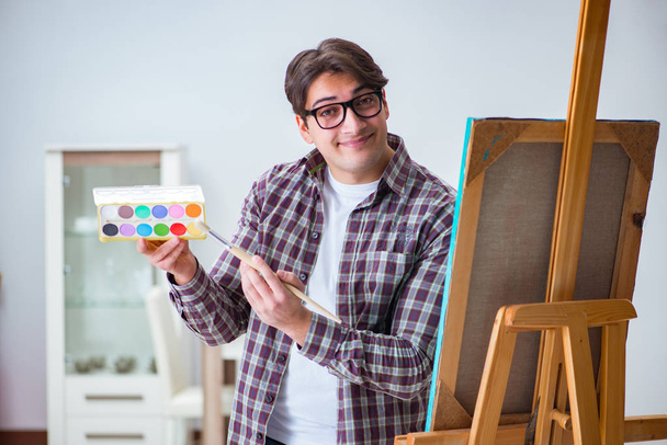 Jonge mannelijke kunstenaar tekening foto 's in heldere studio - Foto, afbeelding