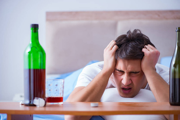 Hombre alcohólico bebiendo en la cama pasando por romper la depresión - Foto, Imagen