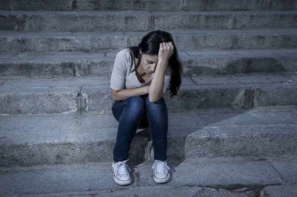 kaunis ja surullinen latino nainen epätoivoinen ja masentunut istuu kaupunkien katu portaikko
 - Valokuva, kuva