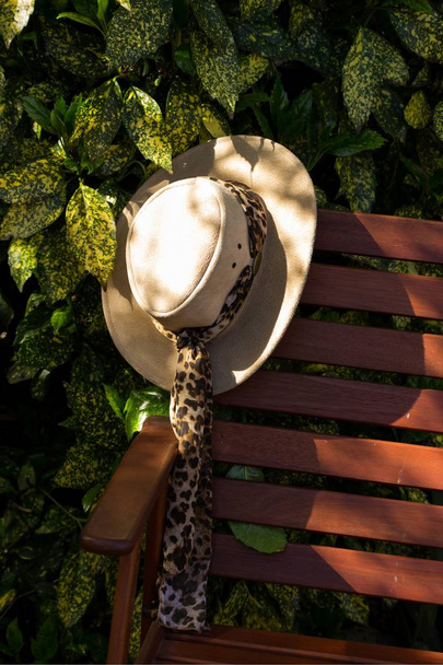 солнечная шляпа, оставленная на садовом стуле в солнечный день
 - Фото, изображение