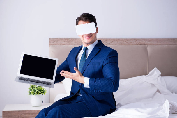 Zakenman draagt een virtual reality headset in de slaapkamer - Foto, afbeelding