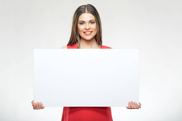 Smiling woman wearing red dress holding white sign board. - Foto, afbeelding