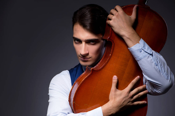 Young man playing cello in dark room - Zdjęcie, obraz