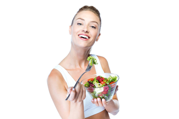 Hermosa mujer joven comiendo ensalada sobre fondo blanco
. - Foto, Imagen