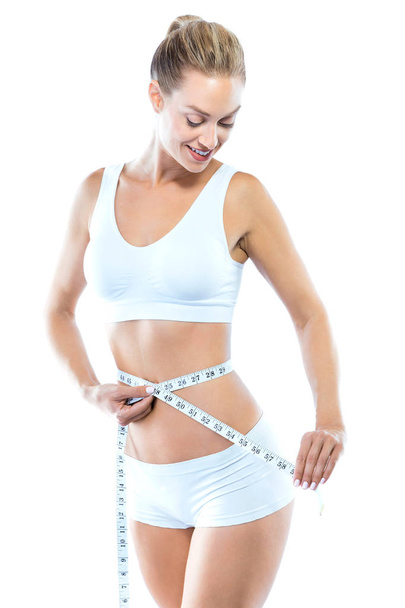 Beautiful young woman measuring her slim body over white background. - Valokuva, kuva