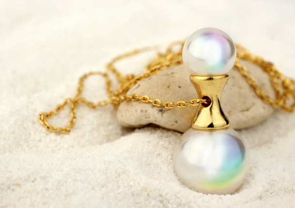 Golden Jewelery pendant with pearls on white sand background, co - Valokuva, kuva