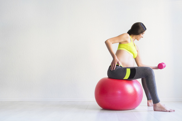 One young pregnant woman doing fitness exercises - Fotó, kép