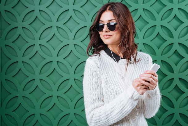 Woman in sweater and sunglasses listening to music  - Photo, Image