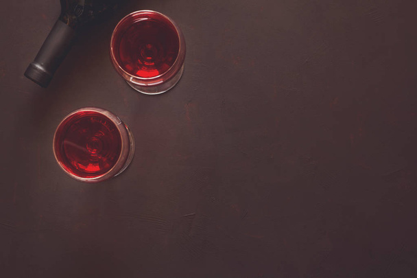 Два бокала вина с красным вином и лежащей бутылкой
  - Фото, изображение