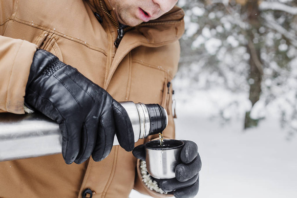 férfi téli erdőben termosz pohár forró itallal - Fotó, kép
