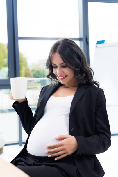 pregnant businesswoman with cup of hot drink - 写真・画像