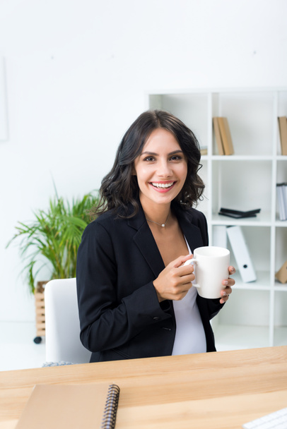 pregnant businesswoman with cup of hot drink - Fotografie, Obrázek