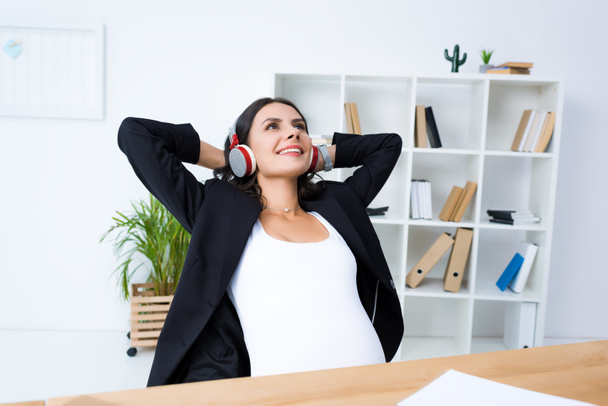 pregnant businesswoman relaxing and listening music - Foto, Imagen