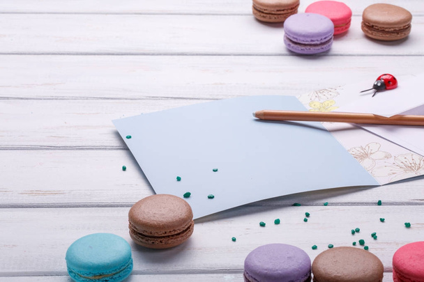 Set of different colorful macaroons Placed over a white wooden background, A postcard and a pencil near the place, Space to write. - Fotoğraf, Görsel