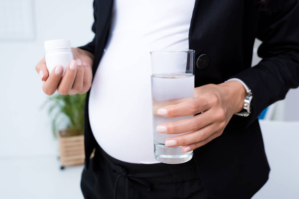 pregnant businesswoman with jar of pills - Фото, зображення