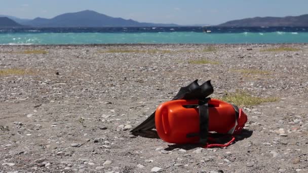 Red rescue buoy standing and pair of swimming flippers. - Footage, Video