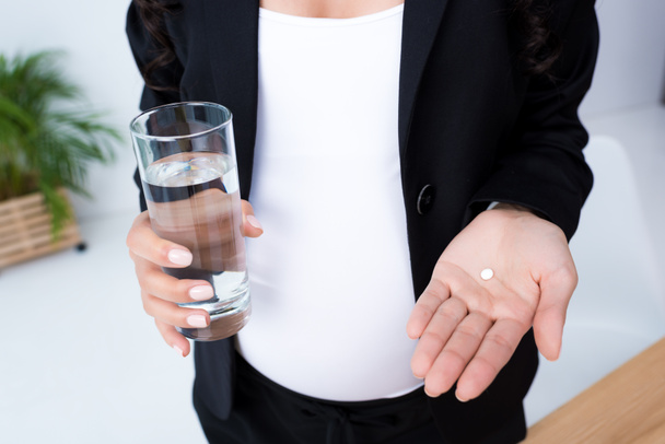 terhes üzletasszony pohár vizet és a tabletták - Fotó, kép