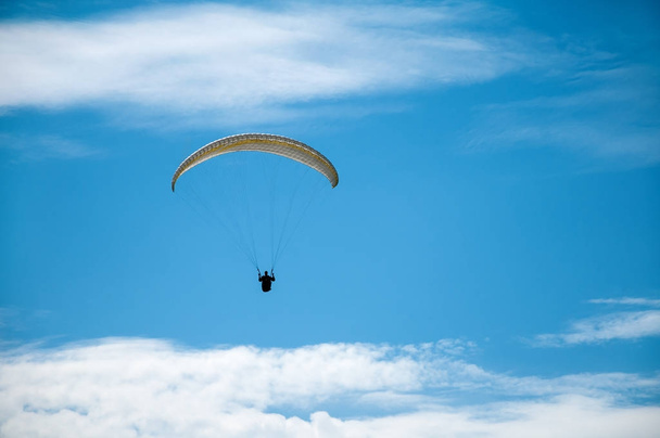 Paraglider vliegen in de blauwe lucht tegen de achtergrond van wolken.  - Foto, afbeelding