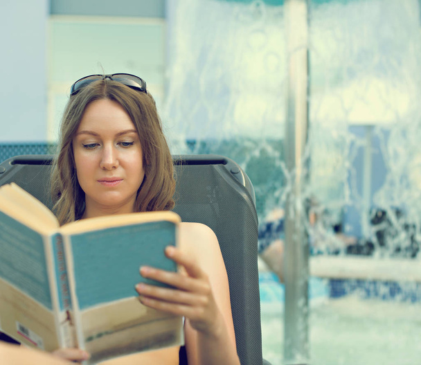 Donna che legge un libro vicino alla piscina d'acqua
. - Foto, immagini