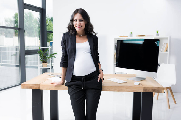 pregnant businesswoman leaning back on worktable - Zdjęcie, obraz