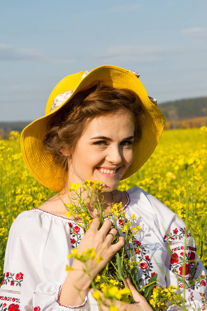 girl in an embroidered shirt among the blooming field - Фото, зображення