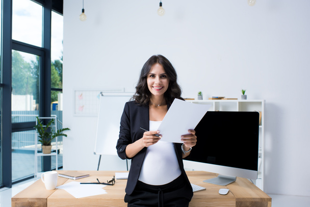 pregnant businesswoman with paperwork - Foto, imagen