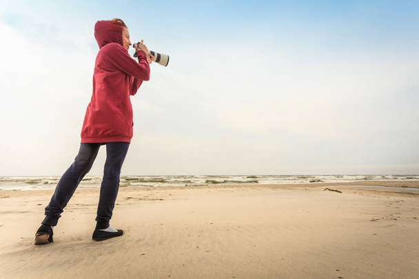 Woman walking on beach with camera - Foto, Bild