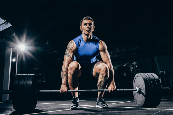 athletic sportsman lifting barbell - Foto, afbeelding