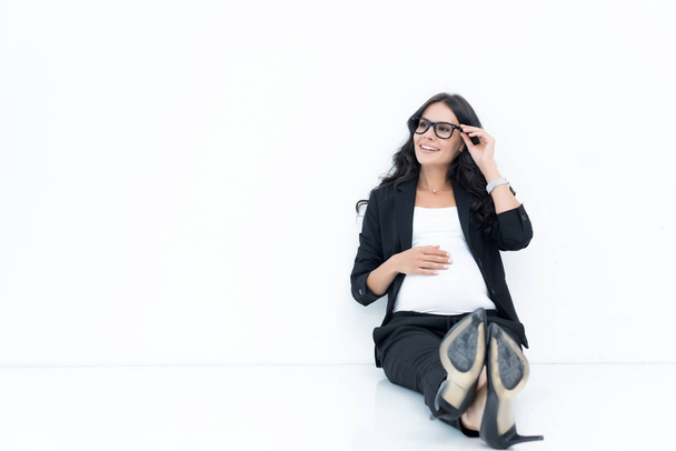вагітна бізнес-леді сидить на підлозі
 - Фото, зображення
