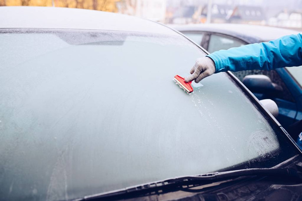 Женщина вытаскивает лед из лобового стекла автомобиля стеклянным скребком
. - Фото, изображение