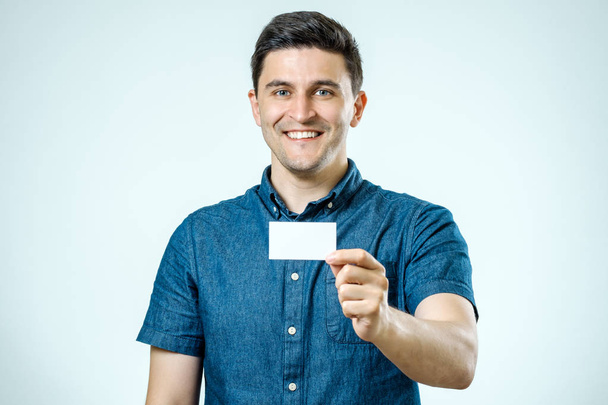 Young man showing blank business card or sign - Valokuva, kuva