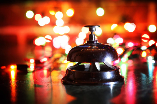 reception bell on table and color shining garland on background - Photo, Image