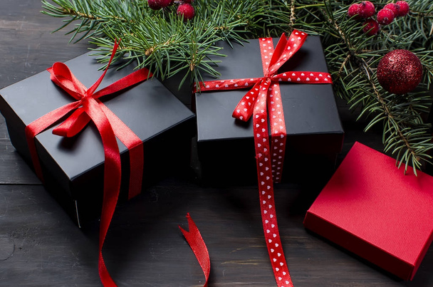 Caixa de presente de Natal preto e vermelho com fita vermelha e farelo de abeto
 - Foto, Imagem