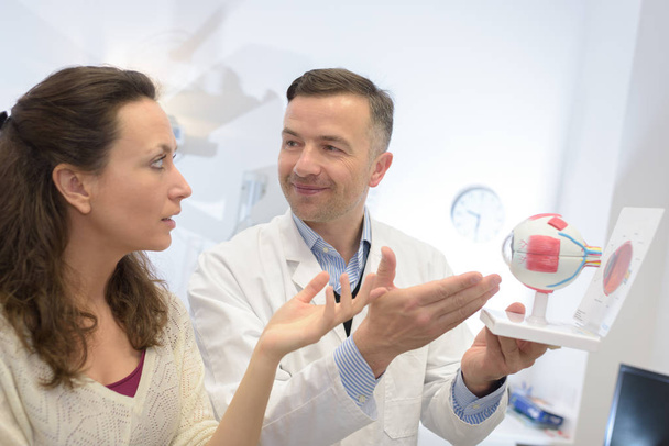 Doctor showing model of the eye to patient - Fotoğraf, Görsel
