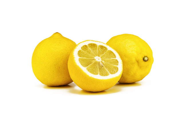 Two whole yellow lemon and one cut half on a white background - Foto, imagen