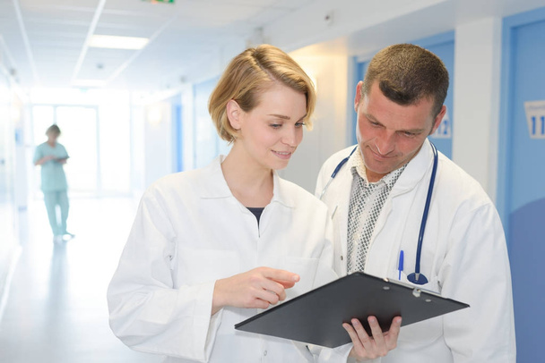 two doctors with clipboard at hospital corridor - Valokuva, kuva