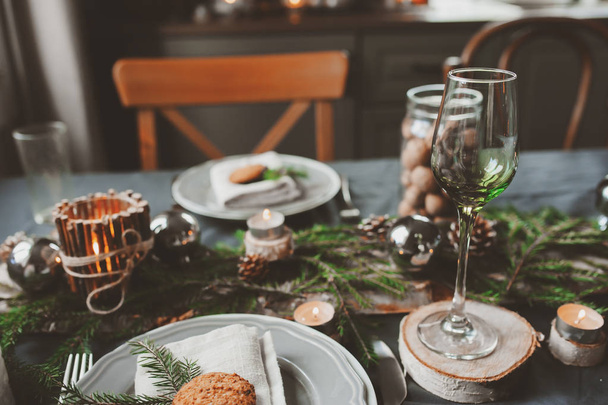 Festive Christmas and New Year table setting in scandinavian style with rustic handmade details in natural and white tones. Dining place decorated with pine cones, branches and candles - Foto, afbeelding