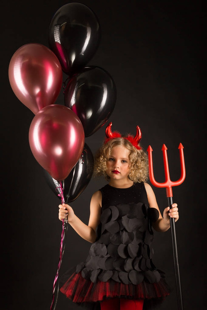 Little girl in devil costume with balloons - Photo, Image