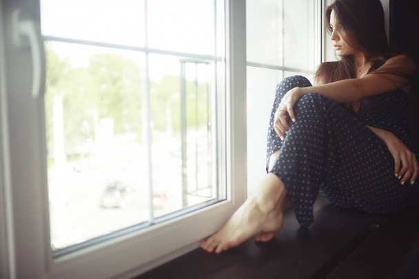 young woman on windowsill - Фото, изображение