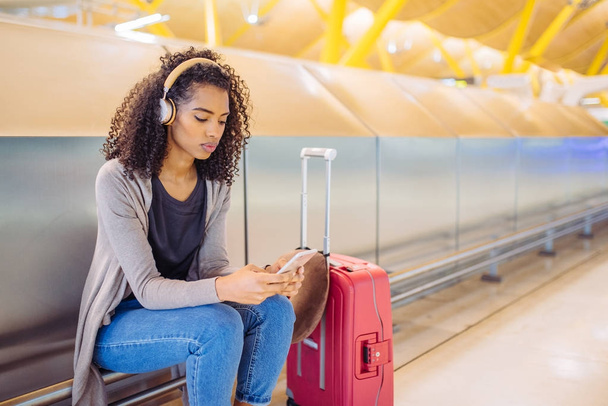 felice giovane donna che ascolta musica con cuffie e telefono cellulare in aeroporto
 - Foto, immagini