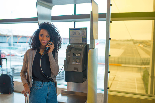mujer feliz en el aeropuerto hablando por teléfono público
  - Foto, imagen